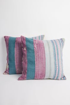 two colorful pillows sitting next to each other on top of a white surface with no one in the photo