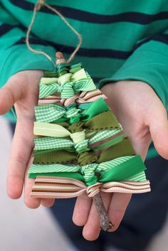 a person holding a small christmas tree ornament in their hands with ribbons tied around it