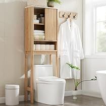 a white toilet sitting next to a wooden shelf filled with towels and other bathroom items