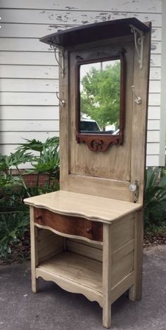 an old dresser with a mirror on top and shelf below it, sitting in front of a house