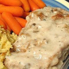 a blue plate topped with meat covered in gravy next to carrots and rice