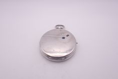 a silver pocket watch sitting on top of a white table