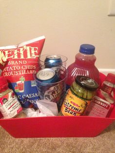 a red basket filled with lots of food and drinks on top of a carpeted floor