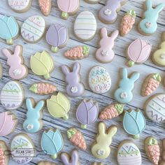 some decorated cookies are laying on a white table with blue and pink ones in the shape of easter bunnies