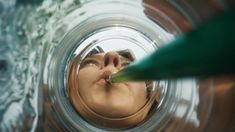 the reflection of a woman's face in a glass jar with water behind it