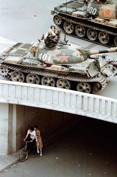 two tanks sitting on top of each other in the street next to a man riding a bike