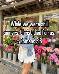 a woman standing in front of flowers with the words while we were still sinners, christ died for us romans 3 8