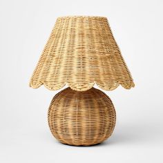 a wicker table lamp with a shade on the top and bottom, in front of a white background