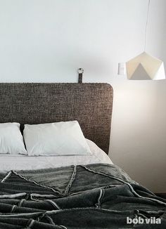 a bed with white pillows and blankets on top of it, next to a lamp