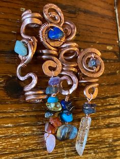 a bunch of different types of jewelry on a wooden table with beads and charms hanging from it