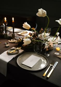 the table is set with silverware and flowers in vases, candles, and napkins