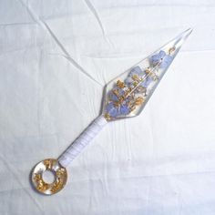 a white and gold colored object with flowers on it sitting on a white cloth covered surface