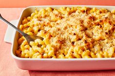 macaroni and cheese in a pink casserole dish with a serving spoon