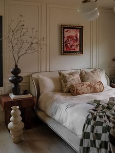 a bedroom with a bed, nightstands and paintings on the wall above it's headboard