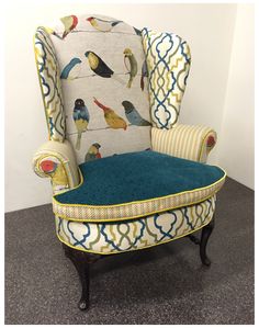 an upholstered chair with colorful birds on the back and arms, against a white wall