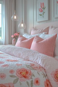 a bed with pink and white comforters in a bedroom next to two lamps hanging from the ceiling