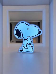 a lit up snoopy dog sitting on top of a white shelf in a room