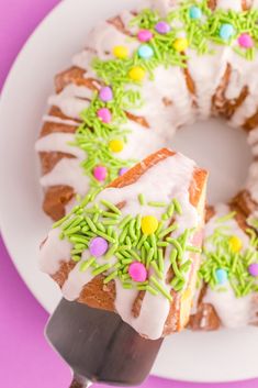 a white plate topped with a cake covered in frosting and sprinkles