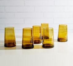 five yellow vases sitting on top of a white table