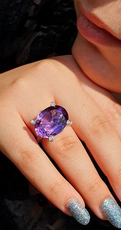 a woman's manicured nails and ring with an amethoraite in the middle