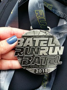 a person holding up a medal in front of their face and wristbands with the words battle run baal printed on it