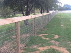 the fence is made of wood and wire, along with some grass in front of it