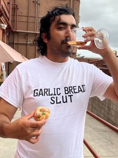 a man drinking from a wine glass while holding a donut in his right hand