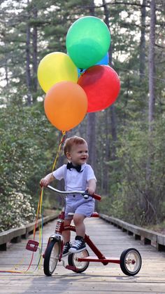 a young boy riding a tricycle with balloons attached to it