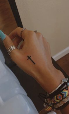 a woman's hand with a cross tattoo on it