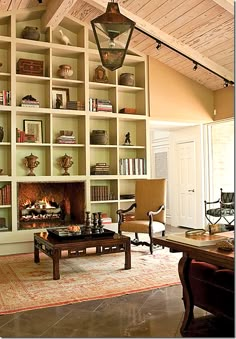 a living room filled with furniture and a fire place under a book shelf covered in books