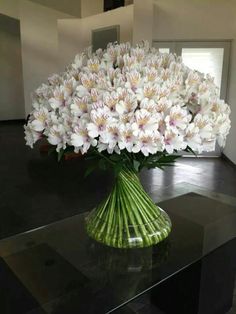 a vase filled with white flowers sitting on top of a black table next to a window