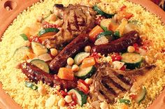 a wooden plate topped with meat and veggies on top of couscous