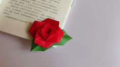 an open book with a red rose on top of it and chinese characters in the background