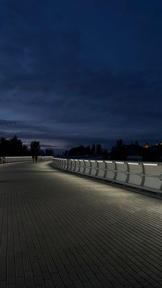 the walkway is lit up at night with people walking on it