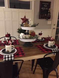 the table is set for christmas dinner with red and black plaid napkins on it