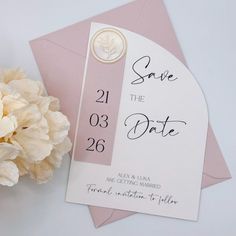 a pink and white wedding save the date card next to a bouquet of carnations