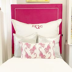 a bed with pink headboard and white pillows