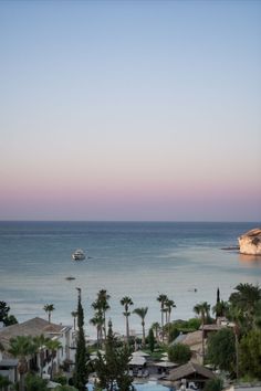 an ocean view with boats in the water and palm trees on the shore at sunset