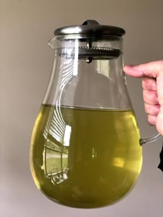 a person holding a glass pitcher with liquid in it and pointing to the bottom that is filled with green liquid