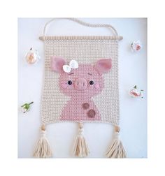 a crocheted wall hanging with a pig on it's face and tassels