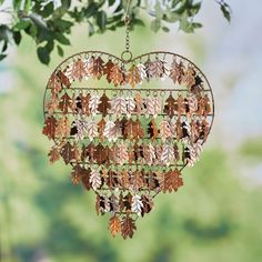 a heart shaped metal decoration with leaves hanging from it's sides on a tree branch