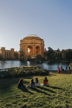 people sitting on the grass in front of a building