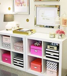 a white desk with lots of drawers and pictures on the wall above it, in front of a mirror