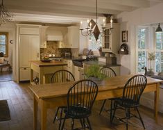 a kitchen filled with lots of furniture next to a dining room table and two chairs