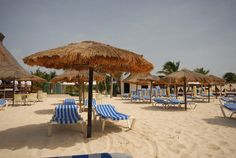 beach chairs and straw umbrellas on the sand at an ocean resort or spa area