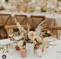 an arrangement of flowers and candles on a table with white linens at a wedding reception