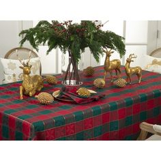 a christmas table setting with gold deer figurines and greenery in a vase