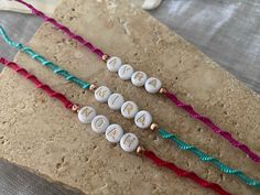 three personalized name necklaces on top of a piece of brown paper with string