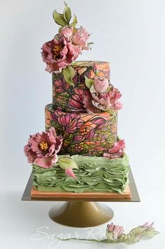 a multi - tiered cake with flowers and leaves on the top is sitting on a plate