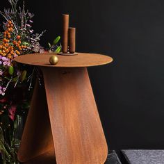 a wooden table with two candles on top and flowers in the backgroung